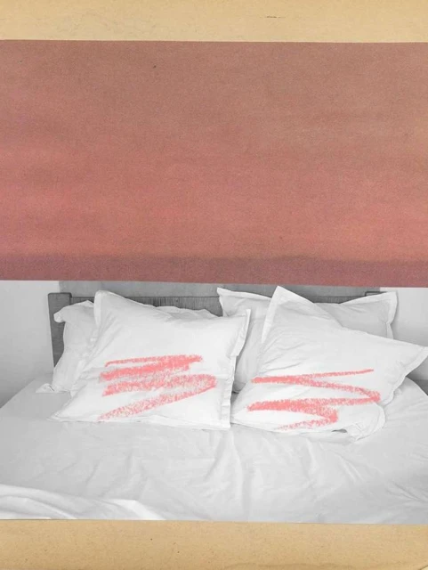 Bedroom interior featuring a white bed with pillows adorned with coral brushstroke patterns against a coral and beige backdrop.