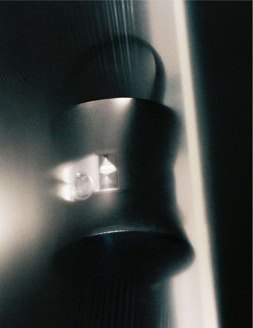 Close-up, low-angle studio shot of a metallic, cylindrical object with light reflecting off its surface, creating an abstract and cool-toned image.