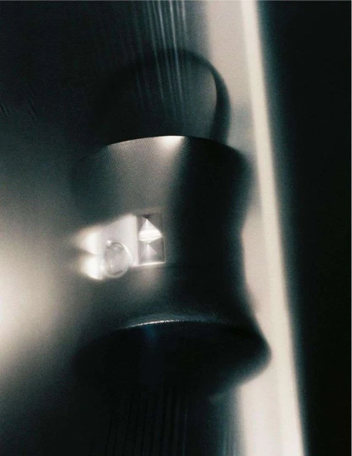 Close-up, low-angle studio shot of a metallic, cylindrical object with light reflecting off its surface, creating an abstract and cool-toned image.