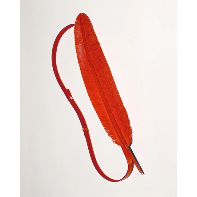 An orange feather with a strap attached to its base, presented on a white backdrop to showcase the material and design.