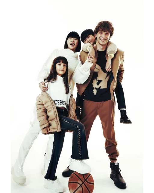 Four young people in stylish casualwear gather in a bright, eye-level studio shot featuring a basketball, promoting youth fashion.