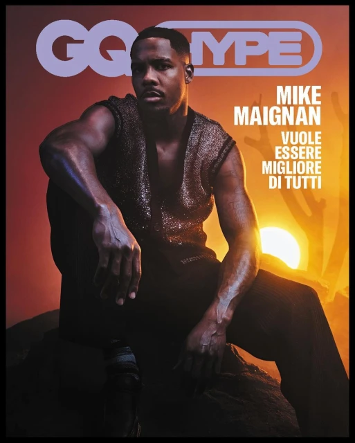 GQ magazine cover featuring Mike Maignan in a sleeveless top, seated against a sunset backdrop, promoting a fashion and entertainment theme.