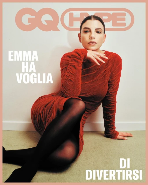Magazine cover featuring a woman in a red dress and black tights sitting on the floor, GQ Hype magazine, indoor setting, warm lighting.