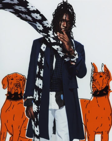 Stylish male model in coat, floral scarf poses with orange cartoon dog graphics on a white backdrop, fashion editorial photography.