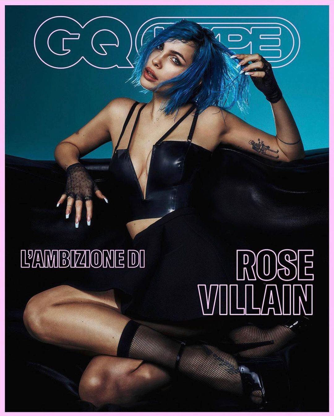 Rose Villain on the cover of GQ Type. Seated pose, wearing black corset top and skirt, blue hair, fishnet stockings, high heels.