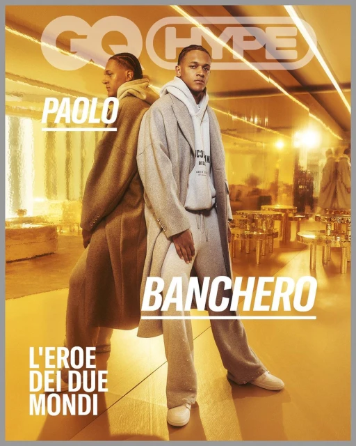 GQ Hype magazine cover featuring Paolo Banchero, an adult male in a grey coat and hoodie, posing indoors with a background of metal furniture.