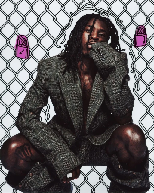 Adult male poses in a grey suit against a wire fence background with pink lock illustrations, creating an edgy fashion statement.