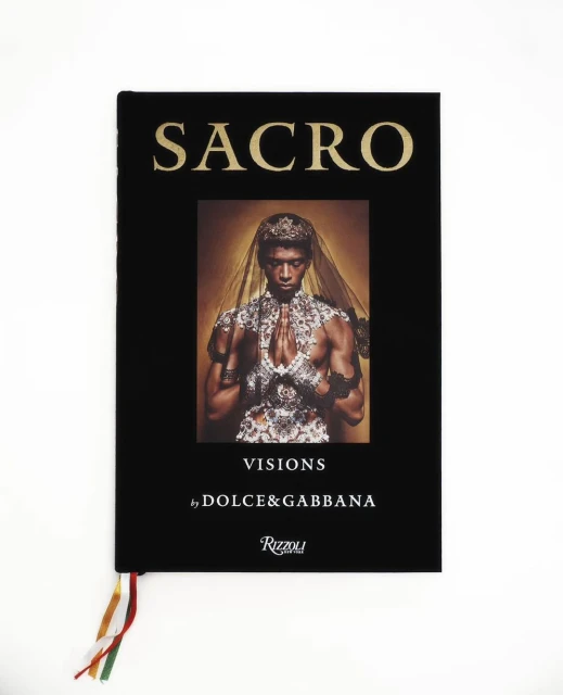 Dolce & Gabbana 'SACRO VISIONS' book cover featuring a portrait of a person in an ornate headdress and jewelry against a black background.