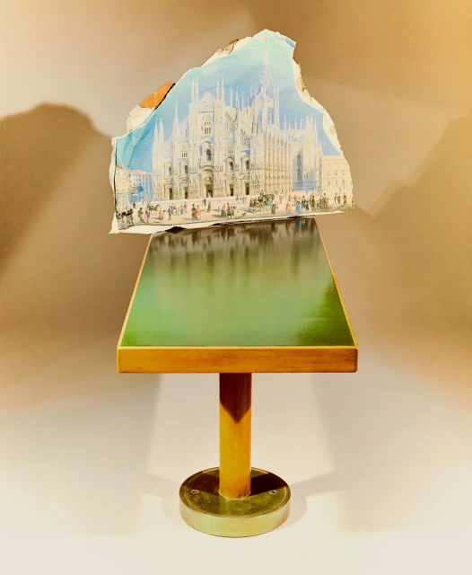 An image shows a green table with a architectural drawing of a building on top, creating a visually striking and artistic composition.