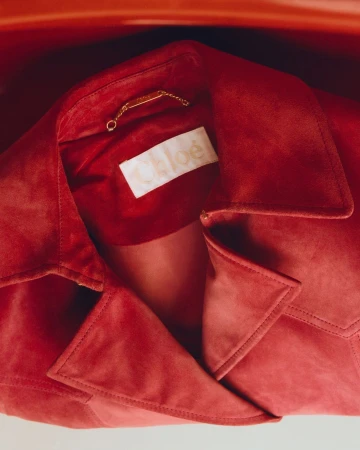 Close-up of a red suede Chloe jacket collar showing the brand label inside, photographed by Mattia Parodi.