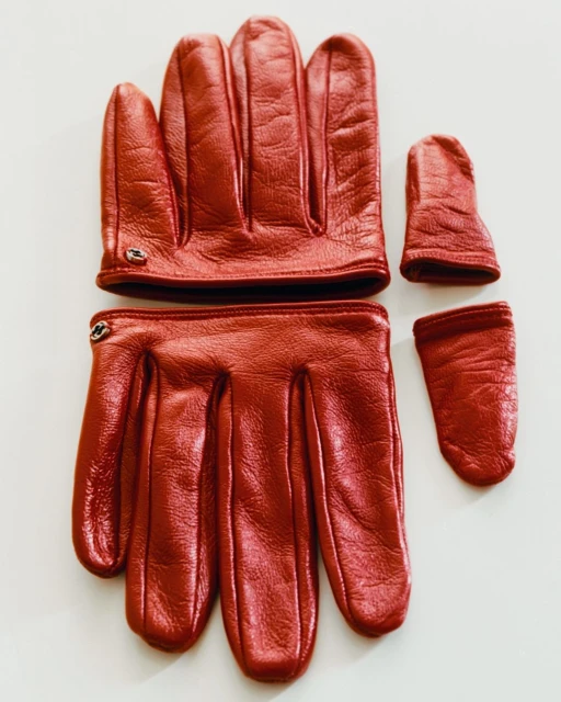 Two pairs of red leather gloves with fingerless tips are laid out on a white surface, showcasing their unique design and craftsmanship.