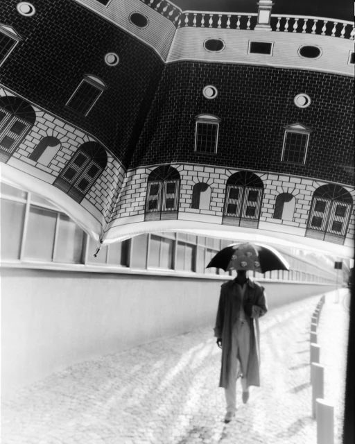 Monochrome outdoor shot of adult wearing trench coat walking with umbrella featuring building illustration on cobblestone street.
