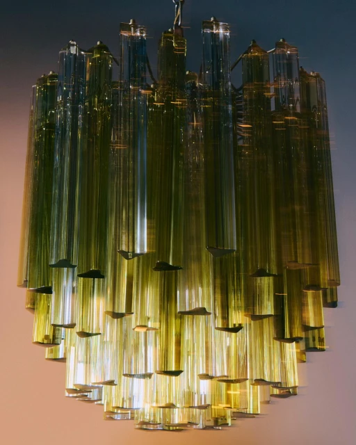 Elegant chandelier featuring numerous vertically hanging translucent tubes and decorative caps in a warm indoor setting.