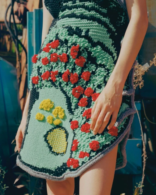 Close-up of a woman wearing a floral-patterned, hand-knitted dress in an outdoor setting with natural lighting.