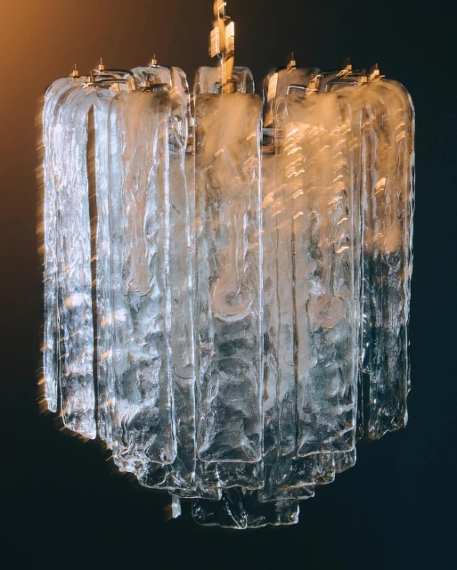 Elegant glass chandelier with tiered design and gold accents, suspended against a dark background, creating a sophisticated atmosphere.