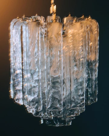 Elegant glass chandelier with tiered design and gold accents, suspended against a dark background, creating a sophisticated atmosphere.