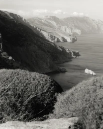 Monochrome landscape photography of rugged coastal cliffs dropping into the sea by Mattia Parodi in Milan