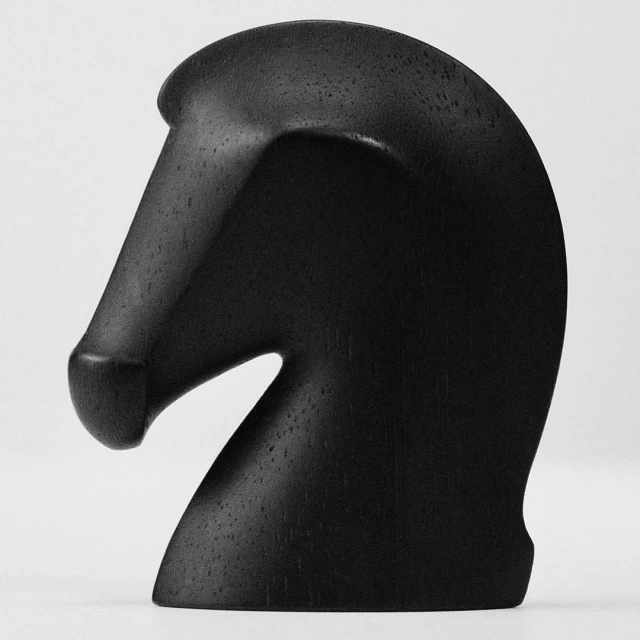 Close-up of a black wooden chess piece in the form of a horse head, set against a soft gray background. Smooth texture is visible.