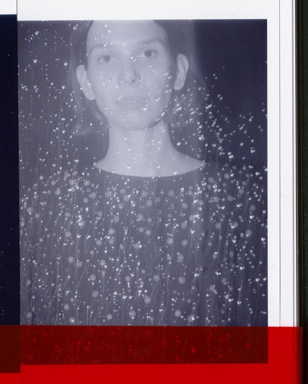 Monochromatic portrait of an adult woman in front of a dark background with superimposed bokeh effect and red and blue overlays.
