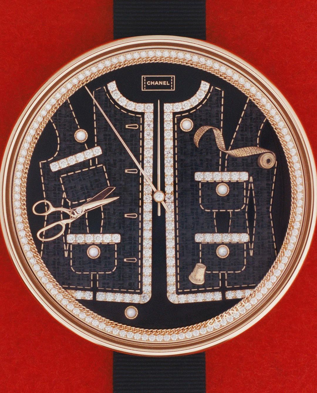 Chanel watch face with diamond jacket design and sewing tools against a red background, showcased in a close-up studio shot.