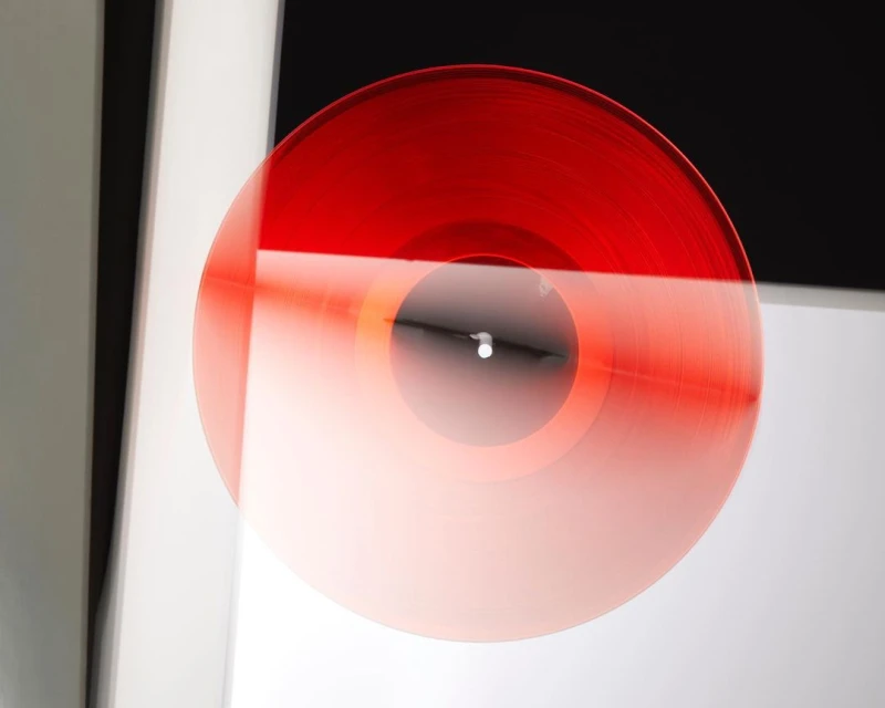 Red vinyl record abstractly floats in a black, white, and gray space. An artistic, conceptual image for music and design.