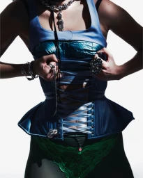 Model wearing blue laced corset top and silver statement jewelry against a bright white seamless background