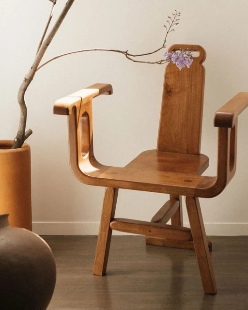 Wooden chair with purple flowers in a minimalist setting featuring a vase and neutral tones. The chair is the dominant element.