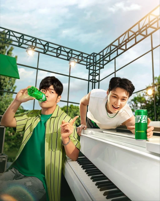 Two Asian men posing outdoors with a drink and a piano under outdoor lighting, showcasing soft drink advertising, lifestyle.