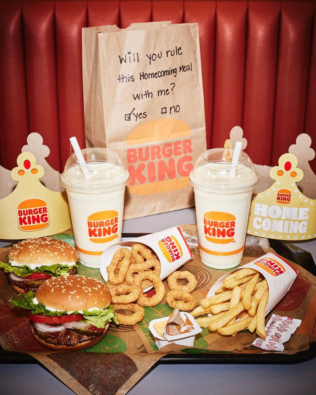 Burger King meal with burgers, fries, onion rings, and milkshakes displayed on a tray with Homecoming themed decorations.