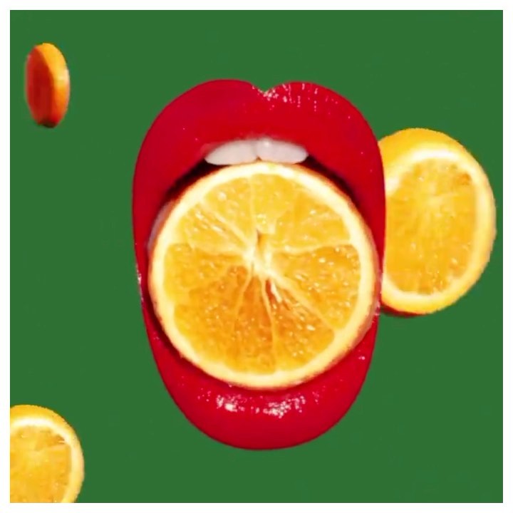Close-up of red painted lips holding a bright orange slice, with other orange halves floating on a green backdrop.