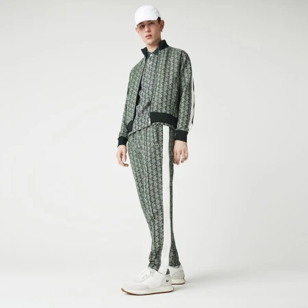 Model in patterned green tracksuit and white cap standing against a white backdrop