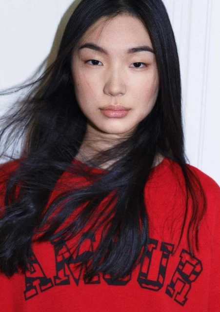 Portrait of a young Asian woman with long black hair wearing a red sweatshirt with the word AMOUR printed on the front.