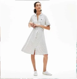 Model in striped zip polo dress and white sneakers against a white seamless background
