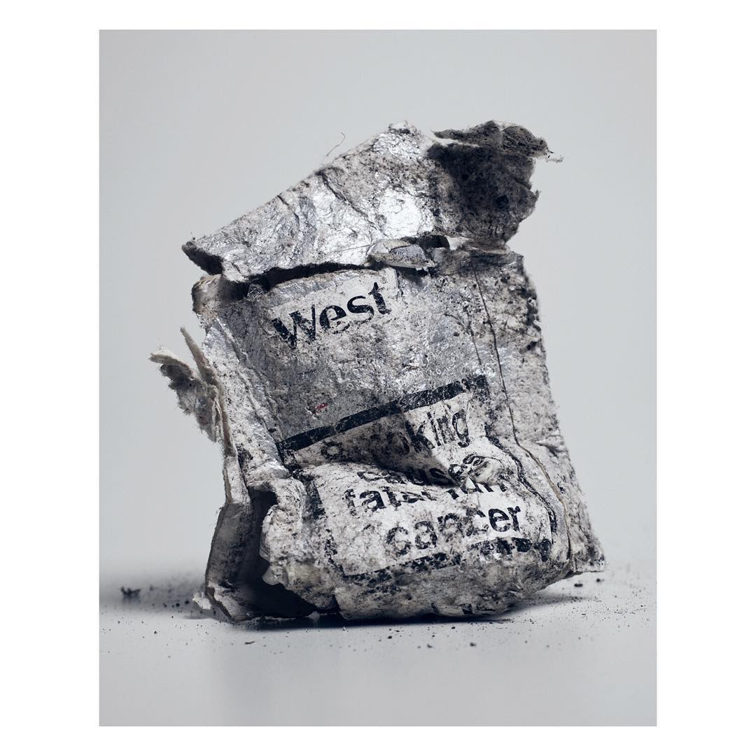 Abstract photography of crumpled paper with the word West visible, suggesting themes of destruction and the ephemeral nature of information.