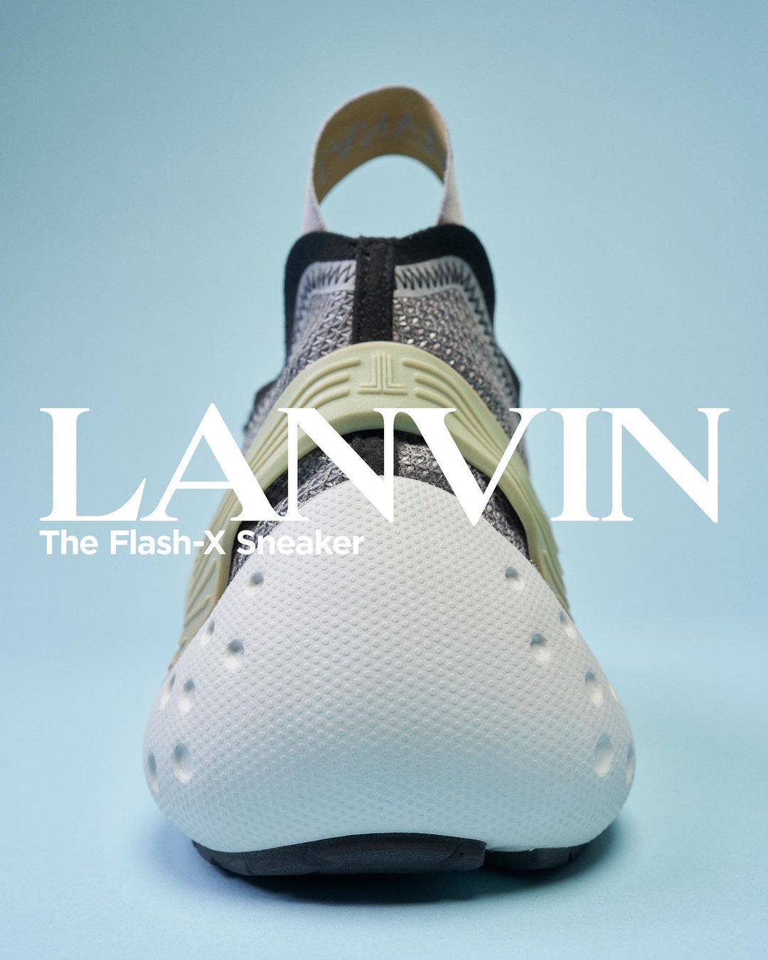 Front view studio shot of a LANVIN The Flash-X sneaker in white, gray and black, with a light blue background. Brand logo visible.