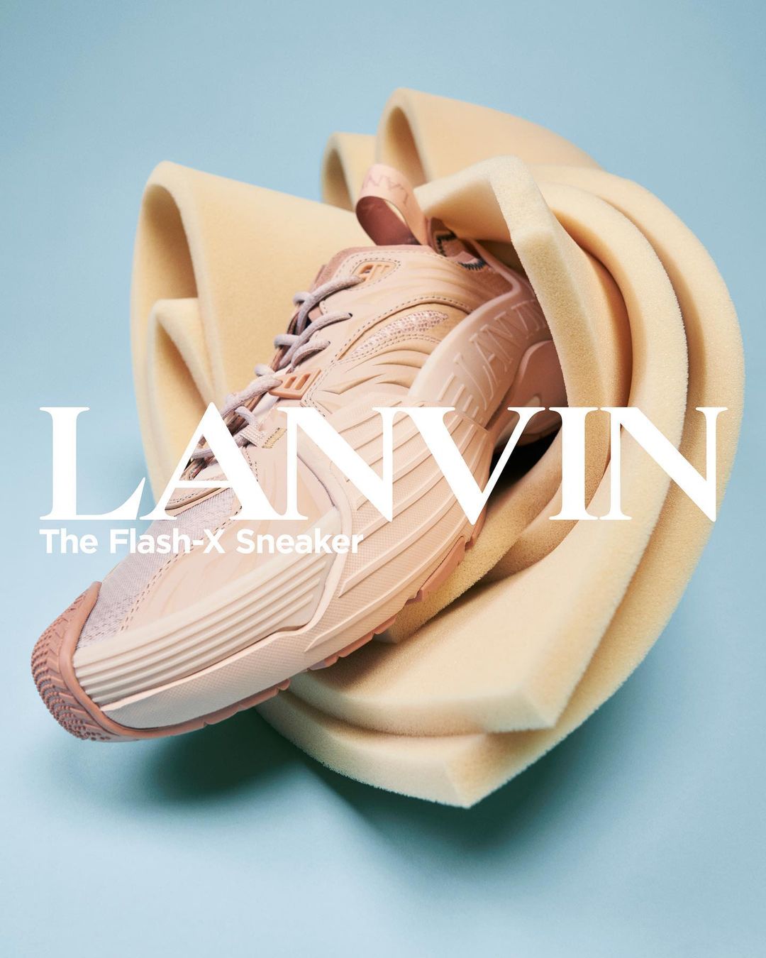Light peach-colored Lanvin Flash-X sneaker, styled with pale orange foam padding, is set against a light blue background in a studio shot.