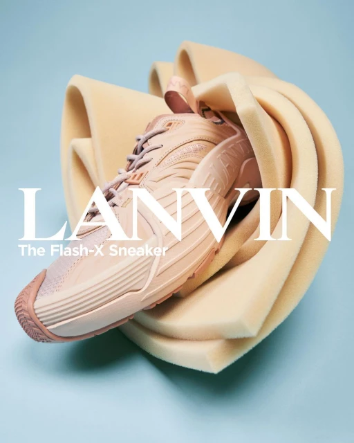 Light peach-colored Lanvin Flash-X sneaker, styled with pale orange foam padding, is set against a light blue background in a studio shot.