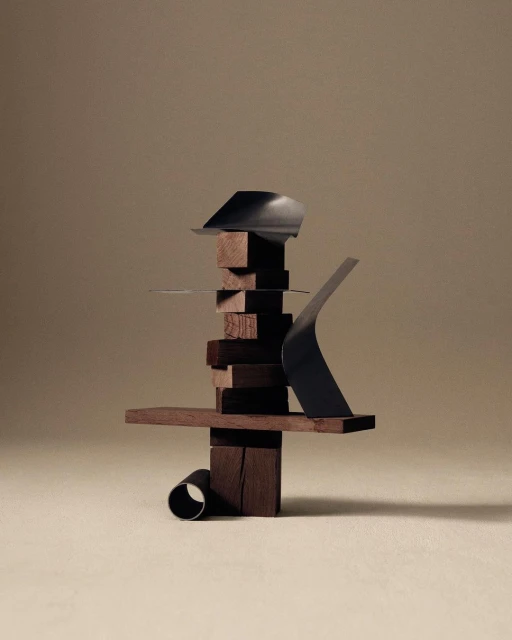 Abstract sculptural composition with dark brown stacked wooden blocks and dark metallic elements on a tan background in studio lighting.