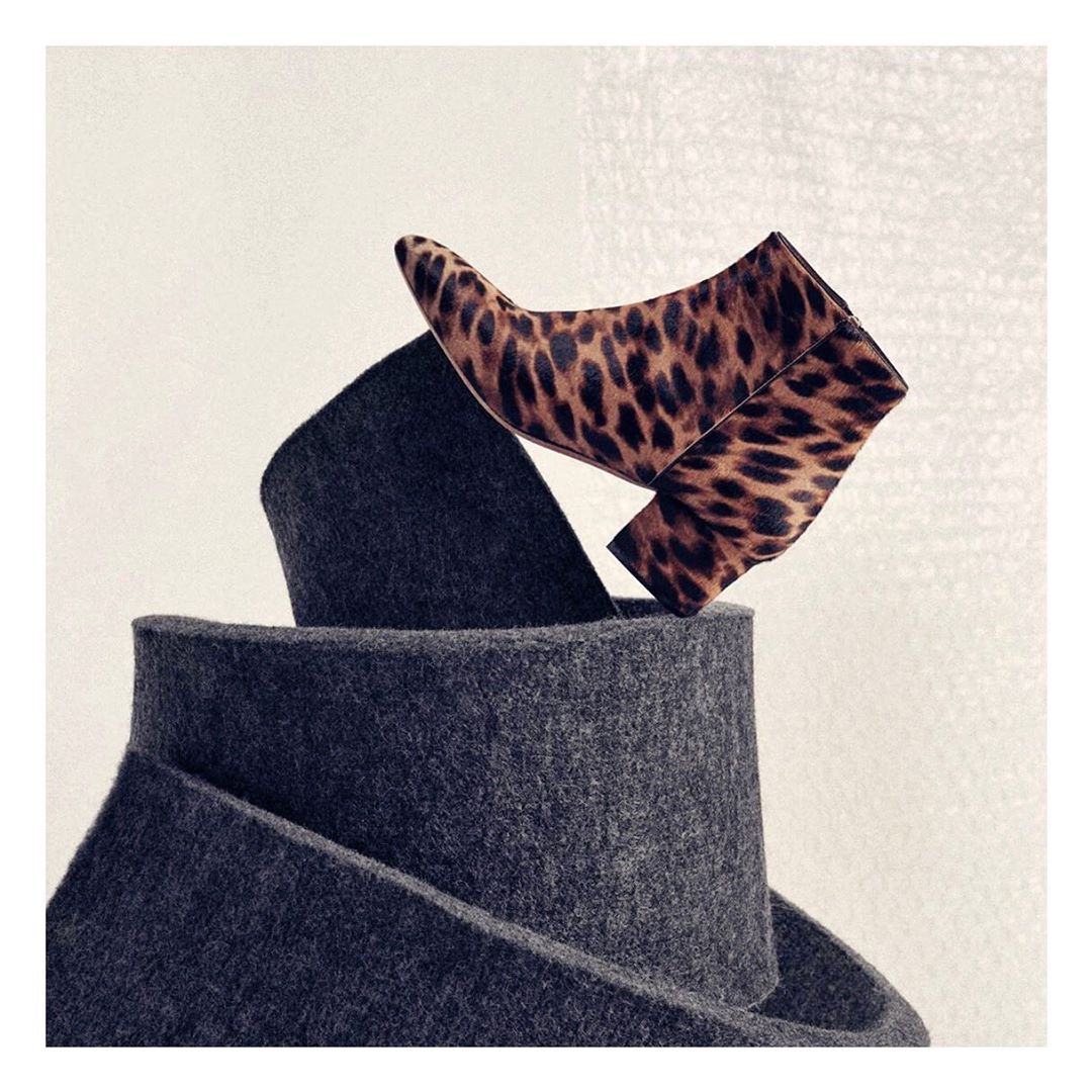 Leopard print ankle boot elevated on a coiled gray textile, studio lighting, fashion-forward design, unique still life composition.