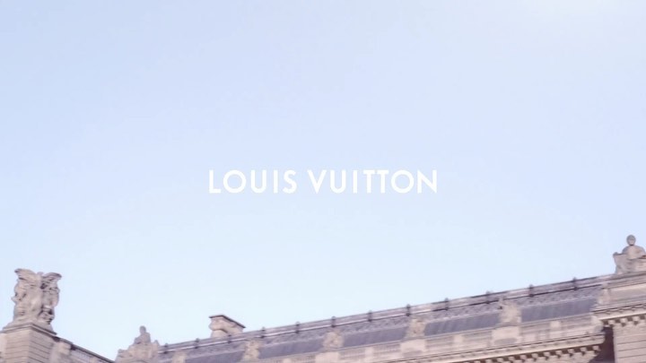 Establishing shot of the Louis Vuitton Foundation building, showcasing its architecture against a clear sky, with the brand name visible.