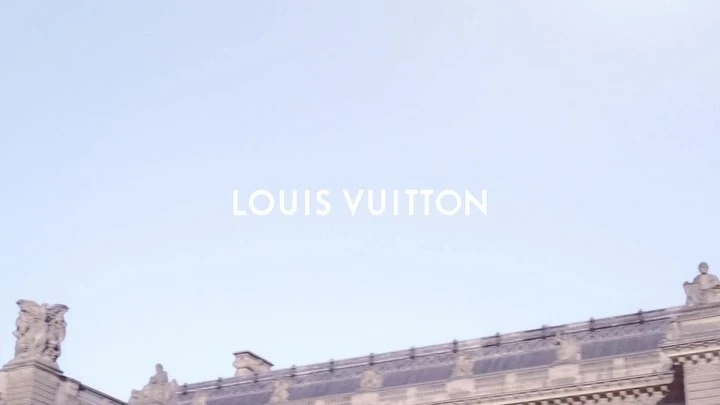 Establishing shot of the Louis Vuitton Foundation building, showcasing its architecture against a clear sky, with the brand name visible.