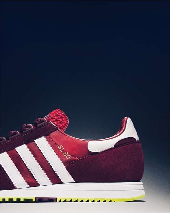 Adidas SL 80 shoe with white stripes and burgundy suede, against a dark background. Focus on the shoe's design and athletic appeal.