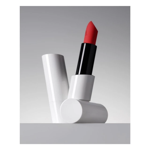Product shot of open red lipstick tube, white packaging, and a neutral background for beauty and cosmetic product photography.