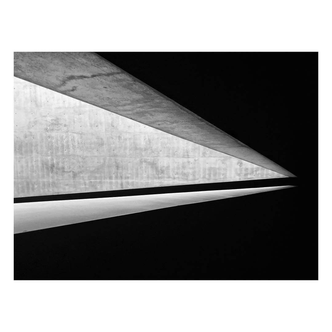 Monochromatic architecture featuring concrete beams and light in a modern interior, emphasizing minimalist design and structural elements.