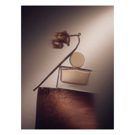 Still life shot of Jason Wu perfume bottle with dried floral elements against a diffused background with muted, earth-toned colors.