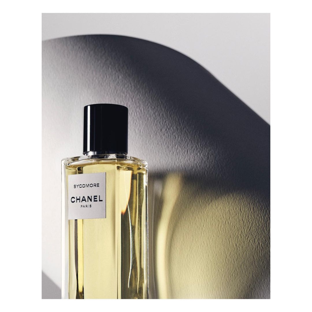Still life shot of a 'Sycomore' Chanel Paris perfume bottle against a gradient background, highlighted with a concentrated light source.
