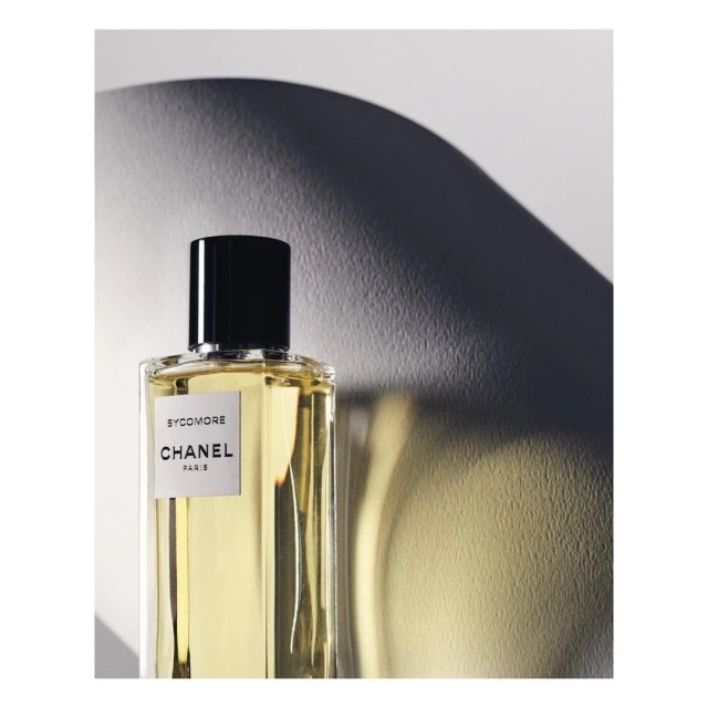 Still life shot of a 'Sycomore' Chanel Paris perfume bottle against a gradient background, highlighted with a concentrated light source.