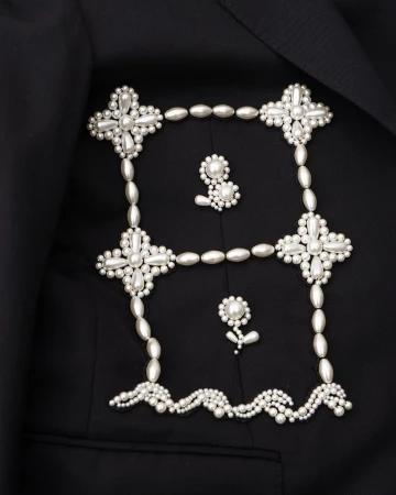 Elegant black blazer featuring unique pearl embellishments forming a square and floral designs, creating a sophisticated fashion statement.