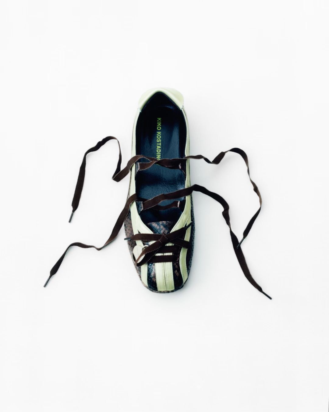 Top-down shot of a Kiko Kostadinov women's shoe with brown laces on a white surface, showcasing its design and style in a minimalist setting.