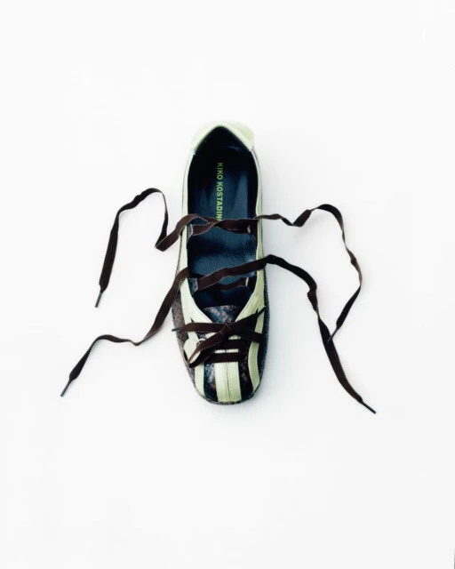 Top-down shot of a Kiko Kostadinov women's shoe with brown laces on a white surface, showcasing its design and style in a minimalist setting.